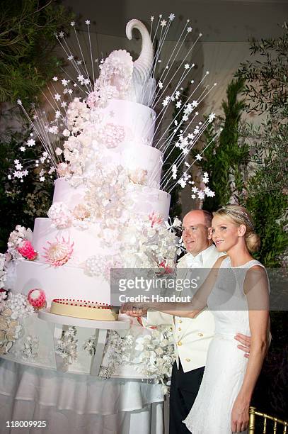In this handout image provided by the Palais Princier, Princess Charlene of Monaco and Prince Albert II of Monaco cut the cake during the religious...