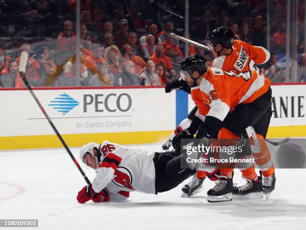 Matt Niskanen and Travis Sanheim of the Philadelphia Flyers trips up Jack Hughes of the New Jersey Devils during the first period at the Wells Fargo...