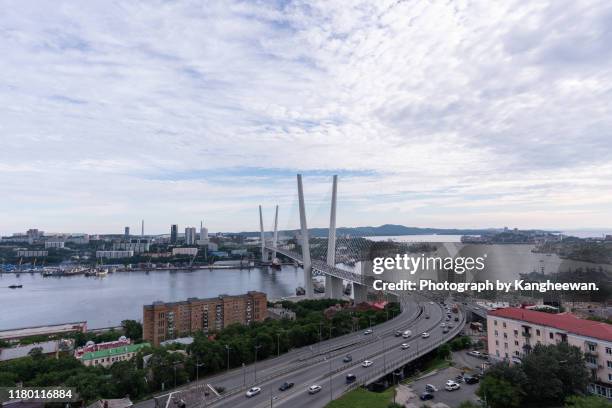 golden bridge over river with buildings in background - vladivostok city stock pictures, royalty-free photos & images