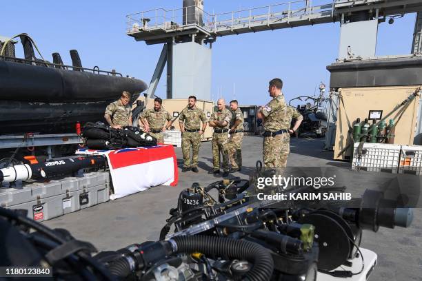British divers aboard Britain's RFA Cardigan Bay landing ship in the Gulf waters off Bahrain stand next to equipment during the International...