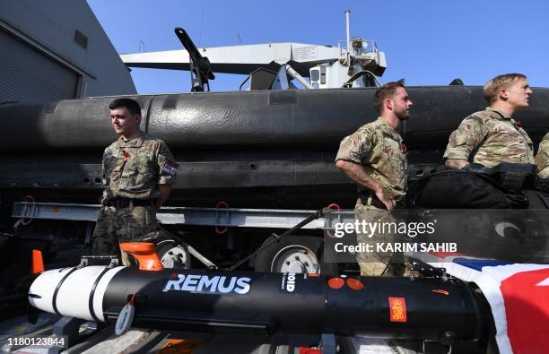 British divers aboard Britain's RFA Cardigan Bay landing ship in the Gulf waters off Bahrain stand next to equipment during the International...