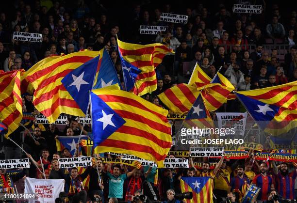 Barcelona's supporters hold placards reading "Spain, sit and talk" and wave Catalan pro-independence "Estelada" flags from the stands during the UEFA...