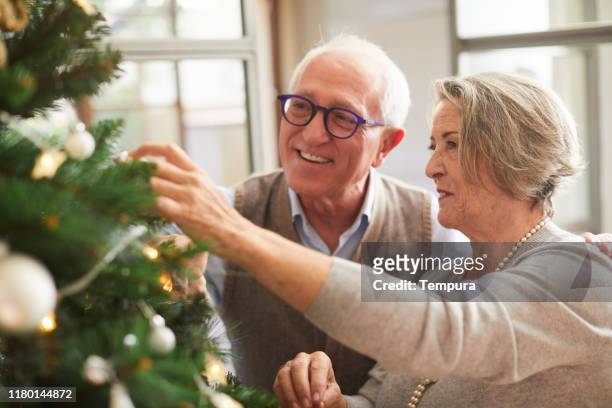 senior couple decorating the christmas tree. - old man woman christmas stock pictures, royalty-free photos & images