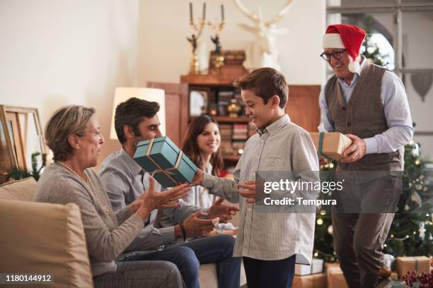 abuelo y nieto dando regalos de navidad al resto de la familia. - family caucasian fotografías e imágenes de stock