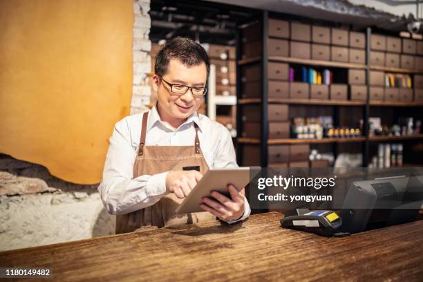 asian shoe store owner using a digital tablet - shoe shop assistant stock pictures, royalty-free photos & images