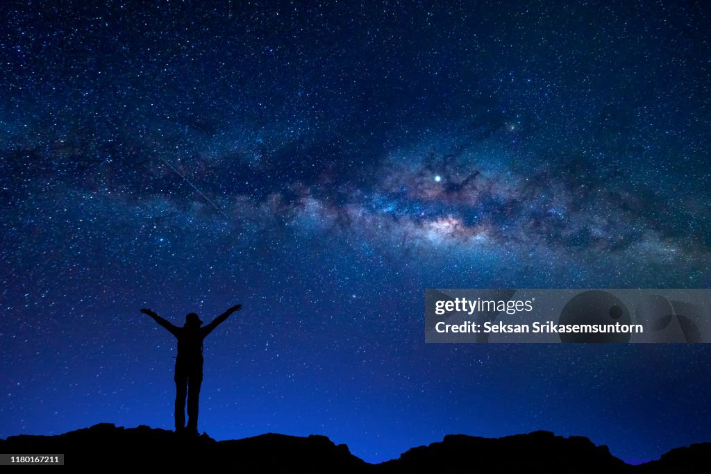 Silhouette of a woman with arms raised among the Milky Way, Night sky