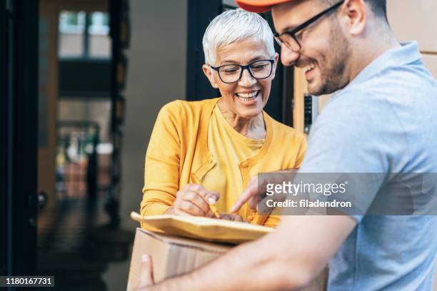 senior woman received the parcel - postal worker stock pictures, royalty-free photos & images