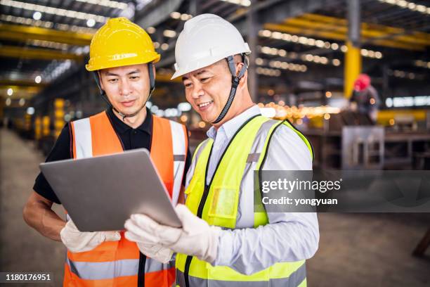 two asian engineers using a laptop in a factory - chinese ethnicity stock pictures, royalty-free photos & images