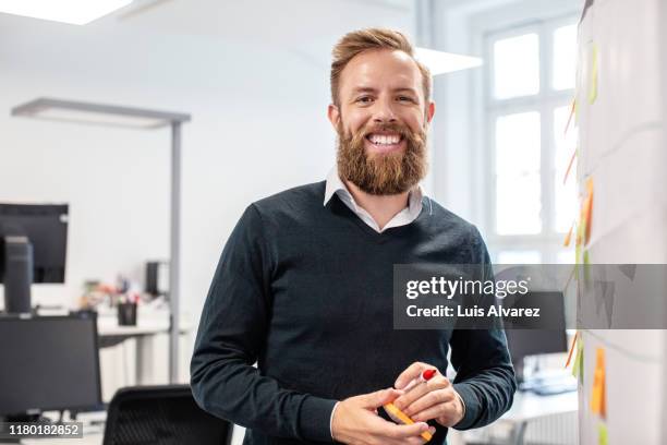 confident businessman standing by bulletin board in office - einzelner mann über 30 stock-fotos und bilder