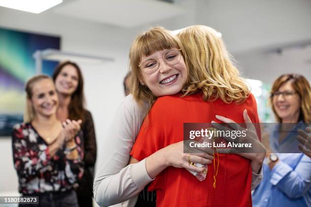 smiling businesswoman embracing colleague in office - women applauding stock pictures, royalty-free photos & images