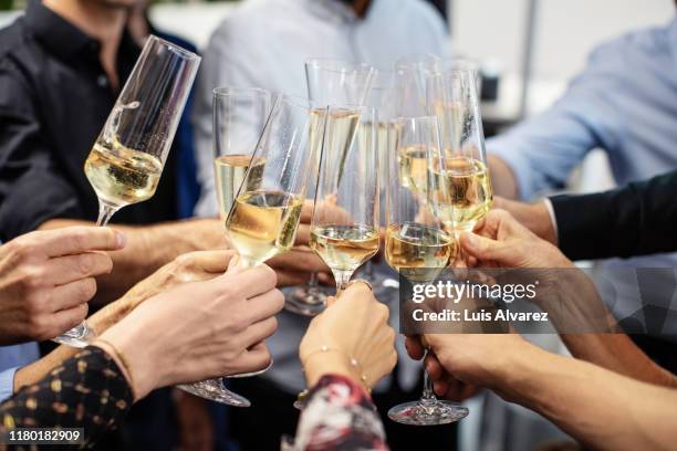 business people toasting champagne flutes in office - sparkling wine stockfoto's en -beelden