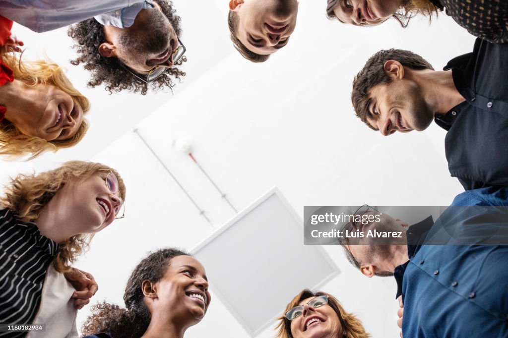 Smiling entrepreneurs huddling together in creative office
