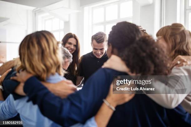 colleagues huddling together in creative office - old woman young man fotografías e imágenes de stock