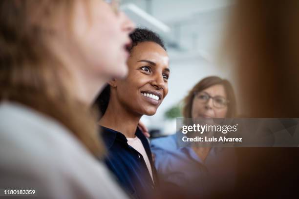 businesswoman huddling with colleagues in office - partenariat photos et images de collection