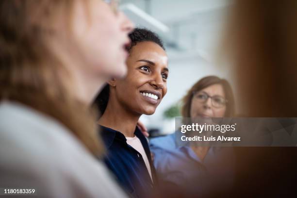 businesswoman huddling with colleagues in office - image focus technique stock pictures, royalty-free photos & images