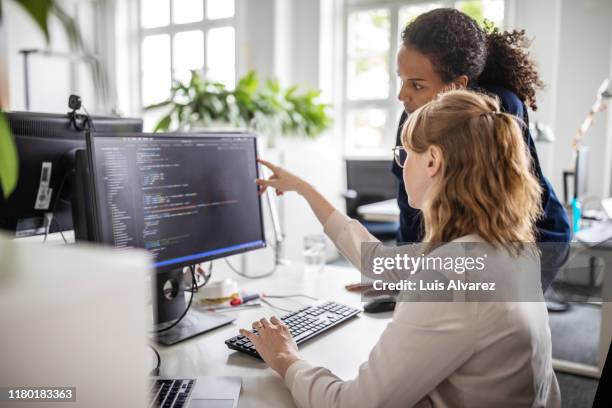 coworkers discussing computer program in office - informatik stock-fotos und bilder