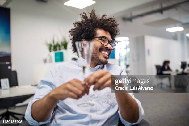 cheerful businessman holding champagne flute in office - work party - fotografias e filmes do acervo