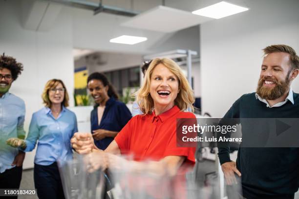 happy businesswoman opening champagne bottle in office - fiesta en la oficina fotografías e imágenes de stock