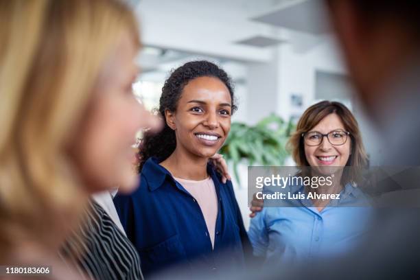 businesswoman huddling with coworkers in office - old man young woman stockfoto's en -beelden