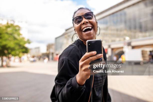 cheerful woman taking selfie in city during vacation - holding sunglasses stockfoto's en -beelden