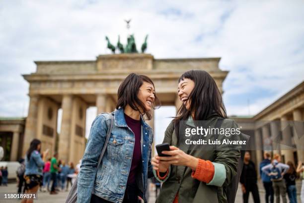 cheerful friends standing against brandenburg gate - foreigner stock-fotos und bilder