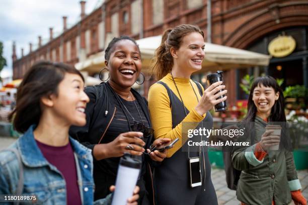 happy female friends with drinks walking in city - happy friends stockfoto's en -beelden
