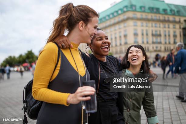 multi-ethnic friends walking in city during vacation - city tour stock-fotos und bilder