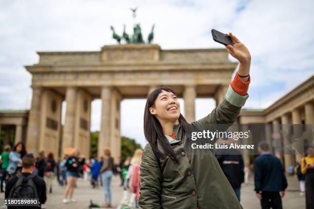 smiling woman taking selfie against brandenburg gate - 記念撮影 ストックフォトと画像