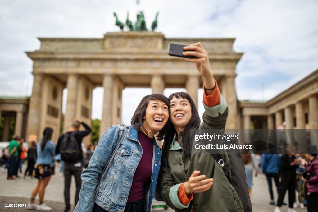 Female friends taking selfie against Brandenburg Gate