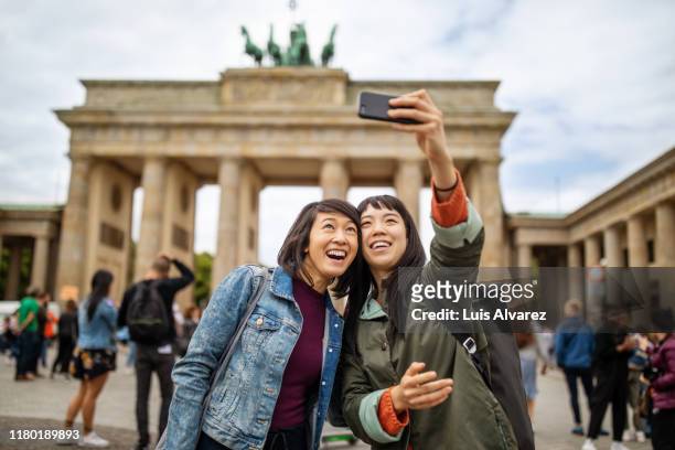 female friends taking selfie against brandenburg gate - self portrait photography stock pictures, royalty-free photos & images