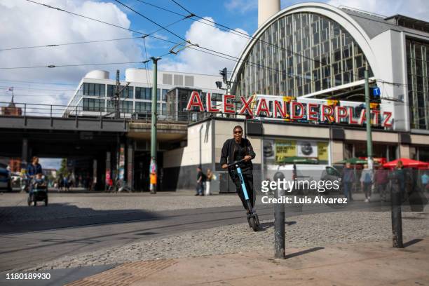 woman riding push scooter in city - berlin stock-fotos und bilder
