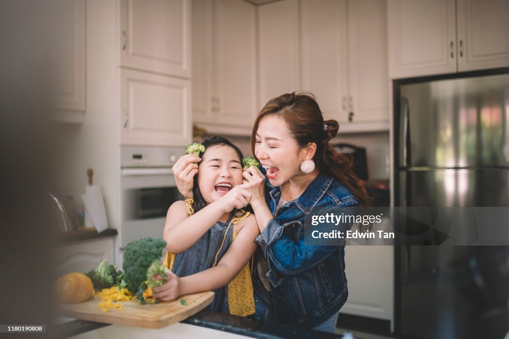 An Asian Chinese housewife having bonding time with her daughter in kitchen preparing food