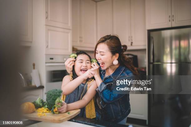 an asian chinese housewife having bonding time with her daughter in kitchen preparing food - chinese ethnicity stock pictures, royalty-free photos & images
