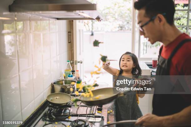 an asian chinese female girl looking at her father cooking in the kitchen preparing food for her and learning - asian family cooking stock pictures, royalty-free photos & images