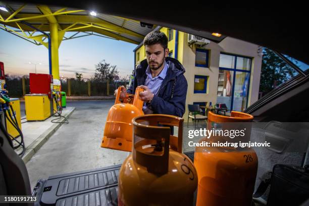 mann steigt aus auto gebrauchte gas butan-zylinder-behälter - gas cylinder stock-fotos und bilder