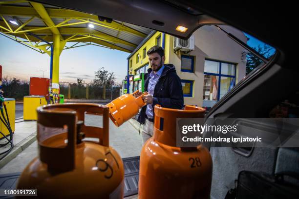 man getting out of car used gas butane cylinder containers - liquefied petroleum gas stock pictures, royalty-free photos & images