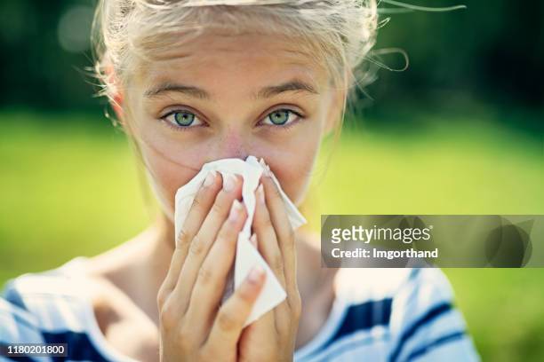 ragazza adolescente con allergia che soffia il naso - bambina bionda occhi verdi foto e immagini stock