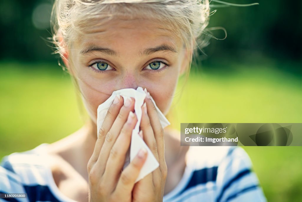 Teenage girl with allergy blowing nose