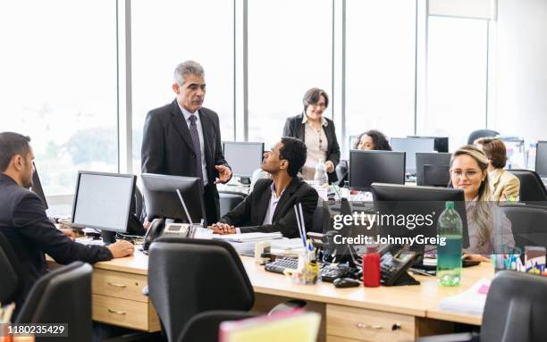 mature business manager talking to office colleague - bustling office stock pictures, royalty-free photos & images