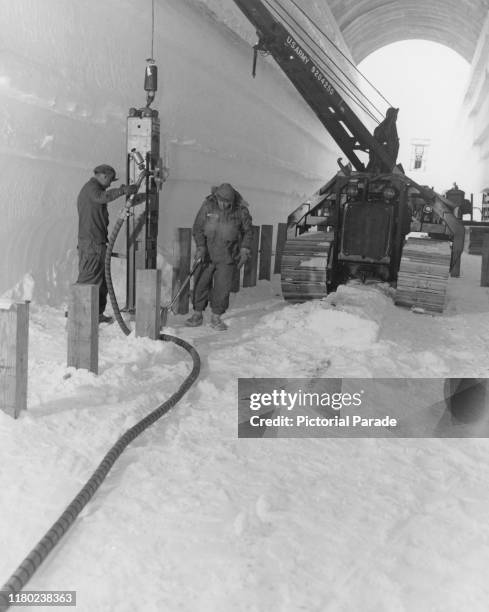Men of the US Army Polar Research and Development Center using a pile-driver to lay the foundations of a 'T5' water storage building at Camp Century,...