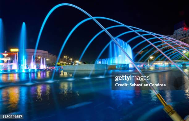 multicoloured fountains along boulevard unirii, in front of romania palace of the parliament, bucharest, romania at night. - bucharest stock pictures, royalty-free photos & images