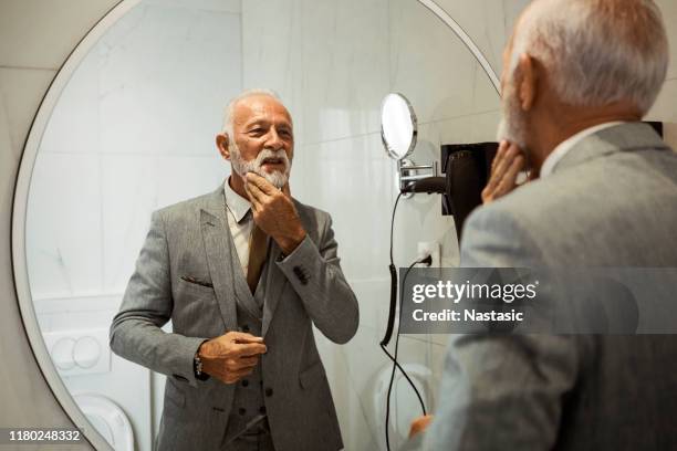 businessman dressing up in bathroom touching his gray beard - adjusting suit stock pictures, royalty-free photos & images