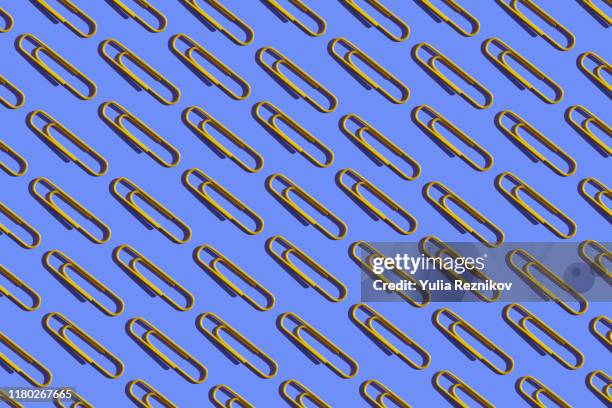 repeated yellow paper clips on the blue background - paper clip stock pictures, royalty-free photos & images