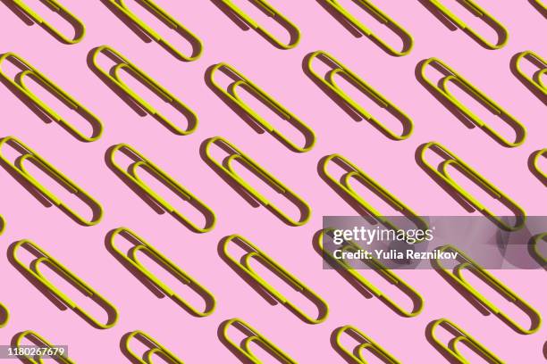 repeated yellow paper clips on the pink background - trombone photos et images de collection