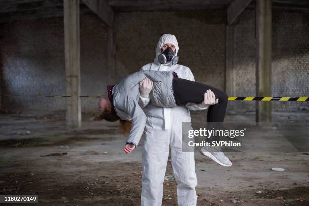 the rescuer carries the injured person in his arms. - radiation sickness stock pictures, royalty-free photos & images