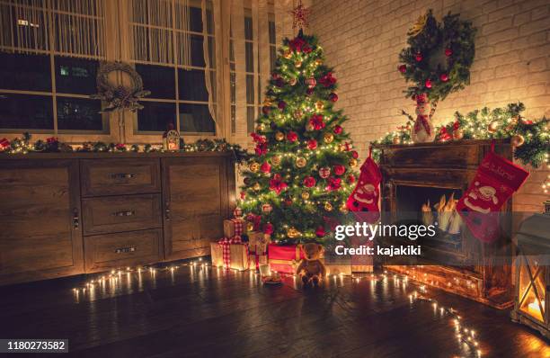 dekorierter weihnachtsbaum in der nähe von kamin zu hause - winter and warm glow stock-fotos und bilder