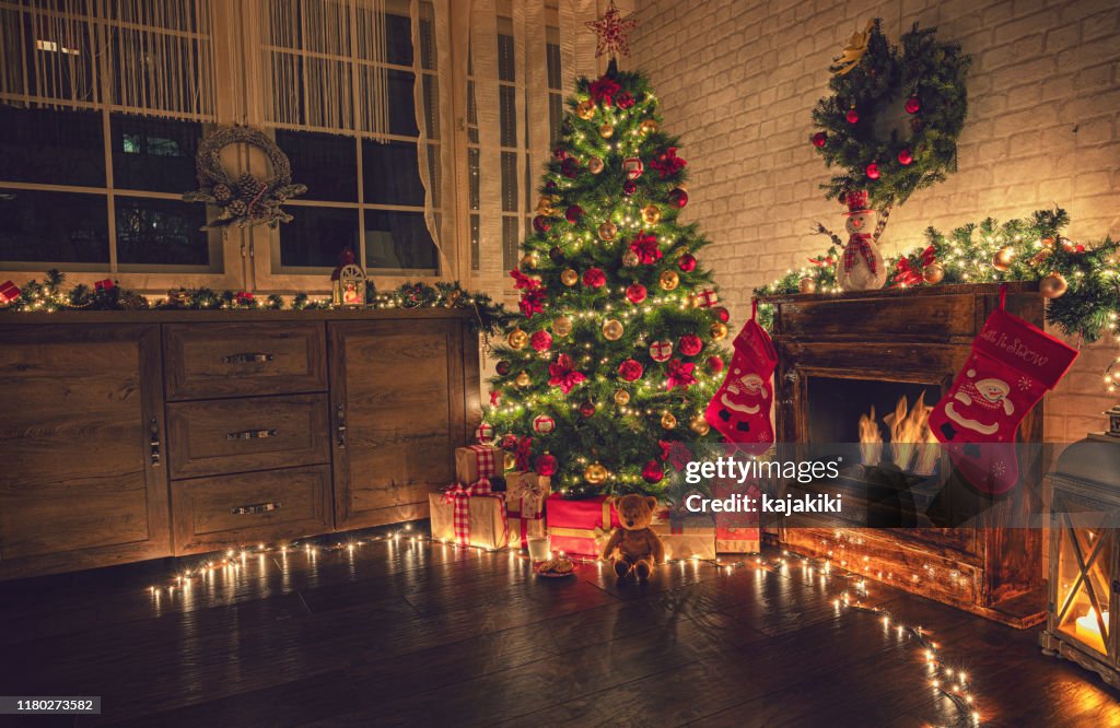 Versierde kerstboom in de buurt van open haard thuis