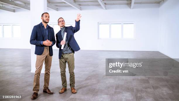 real estate agent talking to entrepreneur in an empty office building - interior design professional stock pictures, royalty-free photos & images