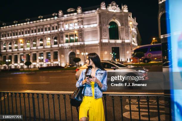 woman with mobile phone in the streets of madrid at night - madrid stock pictures, royalty-free photos & images