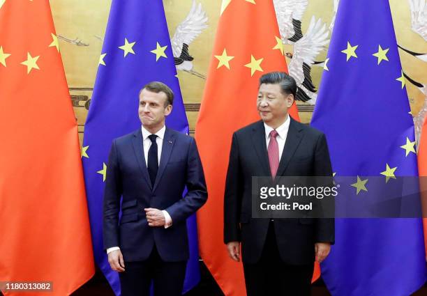 Chinese President Xi Jinping and French President Emmanuel Macron stand in front of Chinese and EU flags at a signing ceremony inside the Great Hall...